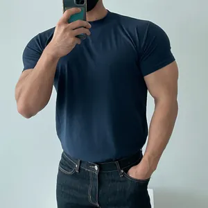 Mirror selfie of a man wearing a dark blue slim-fit athletic T-shirt in detail view