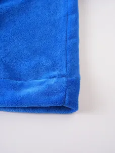 Vue détaillée du tissu en polaire corail bleue douce et des coutures solides sur l'ourlet.
