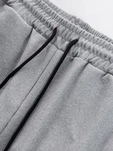 Close-up of grey textured sweatpants featuring elastic waistband and black drawstrings