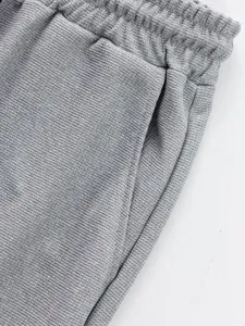 Detailed macro view of grey waffle knit trousers showing elastic waistband and pocket