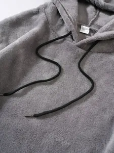 Gros plan d'un sweat à capuche gris en polaire avec cordon noir et étiquette de taille