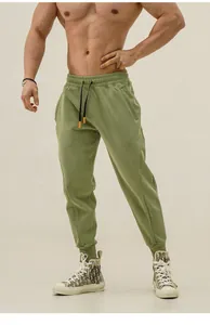 Detail of olive green men's tapered sweatpants with drawstring and zippered pockets.