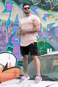 Lifestyle shot of a men's peach slim-fit t-shirt paired with black cargo shorts.