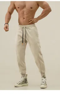 Detail of beige athletic sweatpants with drawstring waist and tapered cuffs