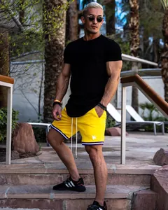 Athletic man in black fitness t-shirt and yellow sports shorts outdoors