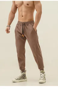 Detail shot of brown men's joggers with drawstring and zipper pockets on a fitness model