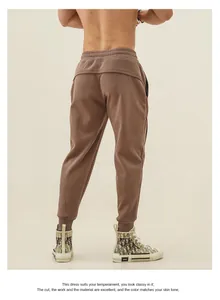 Detail of men's brown tapered cuffed joggers with back pocket design and athletic fit.