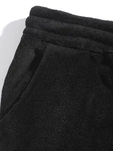 Macro view showing the thick coral fleece texture and pocket of black shorts