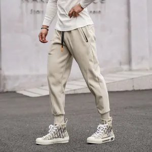 Detail shot of beige men's sports joggers with zippered pockets and ribbed cuffs