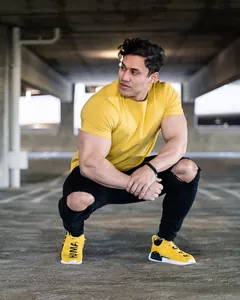 Detail view of a muscular male model wearing a yellow cotton loose athletic T-shirt