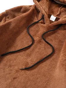 Detailansicht der braunen Fleece-Struktur und des weißen Größenetiketts des Kapuzenpullovers.
