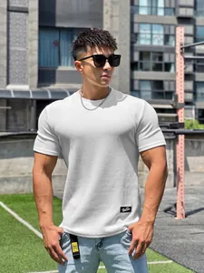 Modello che indossa una maglietta da fitness bianca traspirante in un set all'aperto.