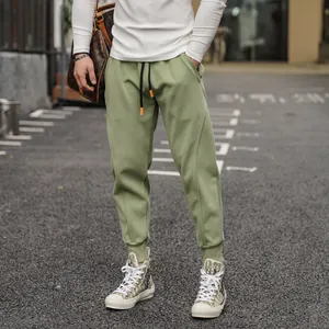 Close-up of green men's joggers featuring drawstring waist and ribbed ankle cuffs.