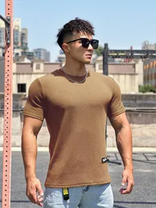 Primo piano di una t-shirt sportiva marrone a maniche corte su un modello di fitness