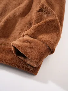 Makro-Detail des weichen braunen Korallenvlies-Stoffs und der Rippbündchen am Herren-Sweatshirt