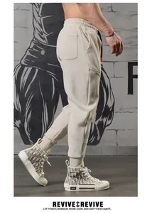 Detail view of beige men's sports joggers with 3D stitching and elasticated cuffs
