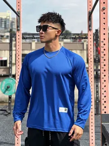 Men's blue long-sleeved mesh athletic T-shirt worn by model in an outdoor gym setting