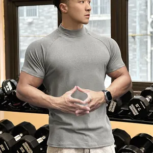Male model wearing a grey mock neck compression T-shirt in a professional gym setting