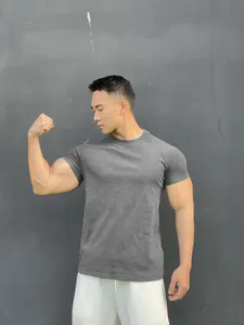 Model wearing a grey short-sleeve fitness t-shirt flexing his arm muscles outdoors