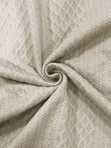 Dettaglio ravvicinato di pregiato tessuto jacquard beige con trama geometrica elegante