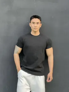 Detailed view of a men's dark grey short-sleeve fitness t-shirt on an athletic model