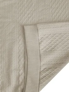 Dettaglio ravvicinato del tessuto a maglia jacquard beige con motivi tessili intricati
