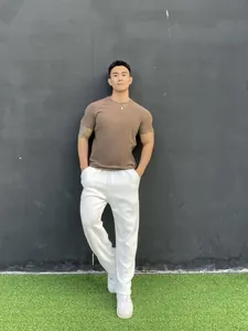 Athletic male model posing in brown crew neck sports t-shirt and white pants outdoors