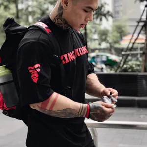 Primer plano de un modelo musculoso con camiseta deportiva de algodón negro y estampado rojo