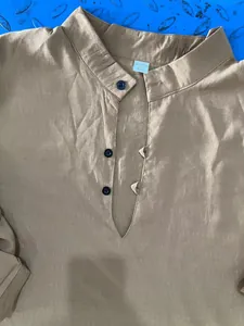 Detailed macro shot of beige linen Henley shirt collar featuring buttons and XXL tag