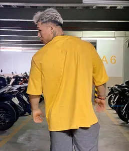 Vista trasera de una camiseta deportiva amarilla de algodón para hombre en un parking.