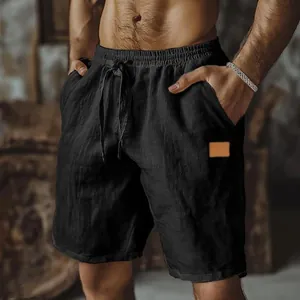 Close-up detail of black cotton linen shorts featuring drawstring waist and a side patch