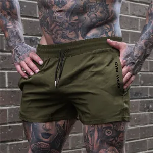 Detail view of army green gym shorts on tattooed model with waist drawstring