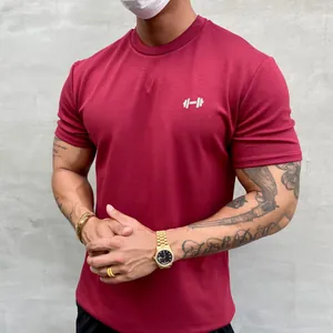 Nahaufnahme eines weinroten Baumwoll-Fitness-T-Shirts für Herren mit Hantel-Logo-Detail