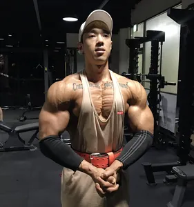 Muscular Asian athlete wearing a beige cotton fitness stringer tank top in a professional gym
