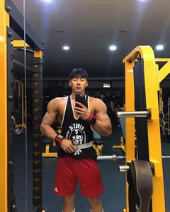 Muskulöser Mann trägt ein schwarzes Gym-Stringer-Tanktop in einem Fitnesscenter