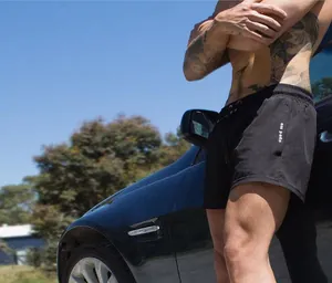 Close-up of lightweight men's black athletic running shorts on a model next to a dark car.