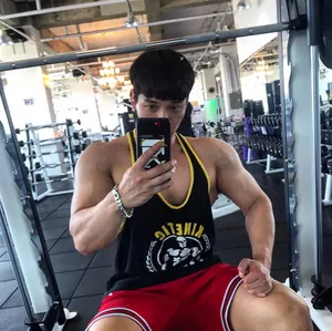 Muskulöser Mann in einem schwarzen Fitness-Tanktop beim Training in einem modernen Gym