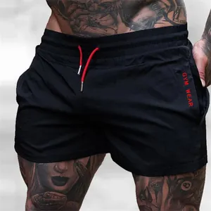 Detail of men's black gym shorts featuring a red drawstring and vertical GYM WEAR print.
