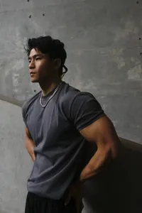 Athletic man wearing a slim-fit charcoal grey crewneck gym t-shirt against a wall