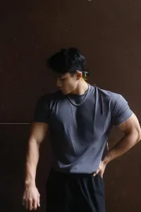 Model wearing a grey heavy slim fit crew neck training T-shirt against a dark wall