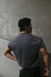 Back view of a men's slim-fit training t-shirt in charcoal grey on an athletic model