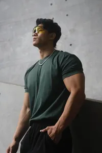 Detail shot of a muscular man in a slim fit dark green heavy weight Sorona training T-shirt.