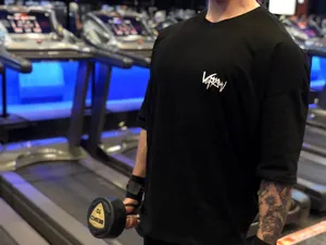 Gros plan d'un homme portant un t-shirt d'entraînement noir surdimensionné en salle de sport
