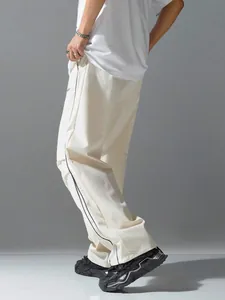 Side view of cream-colored wide-leg track pants with vertical black stripes