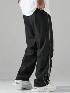 Close-up of men's black high-street parachute pants with side stripes and quick-dry fabric