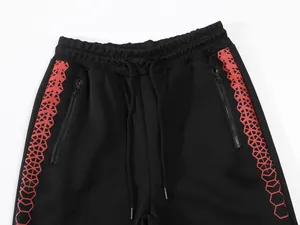 Detailansicht der schwarzen Sporthose mit roten geometrischen Mustern und Reißverschlusstaschen