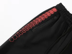 Detailansicht einer schwarzen Jogginghose mit rotem Sechseck-Print und Seitentasche