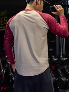 Back view of men's raglan long sleeve fitness T-shirt with color-block design in a gym