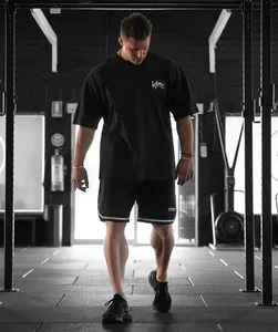 Détail d'un t-shirt de sport noir ajusté porté par un homme dans une salle.
