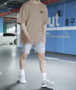 Modèle portant un t-shirt en coton oversize beige et un short gris dans un parking